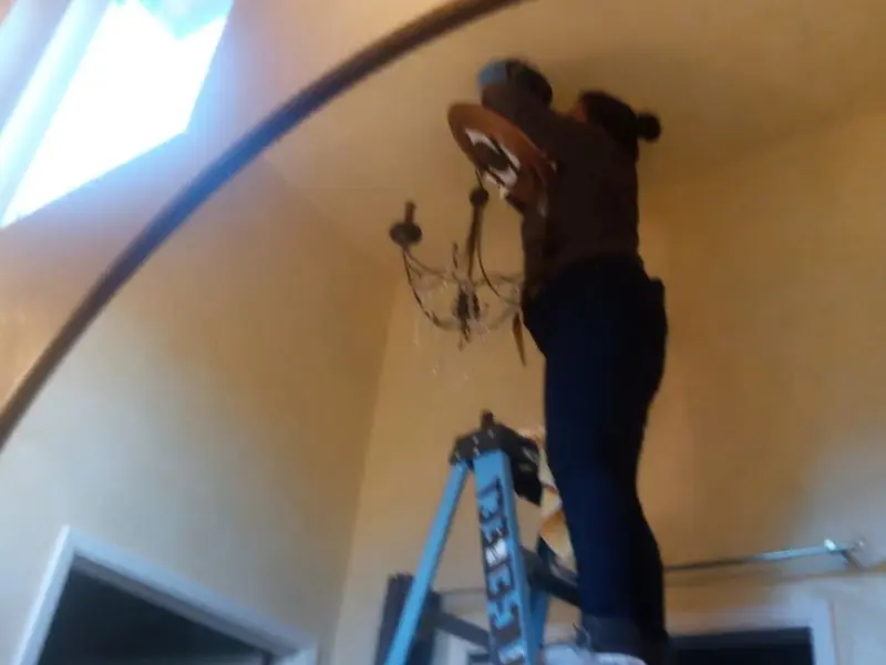 Electrician installing a chandelier in a La Porte residence